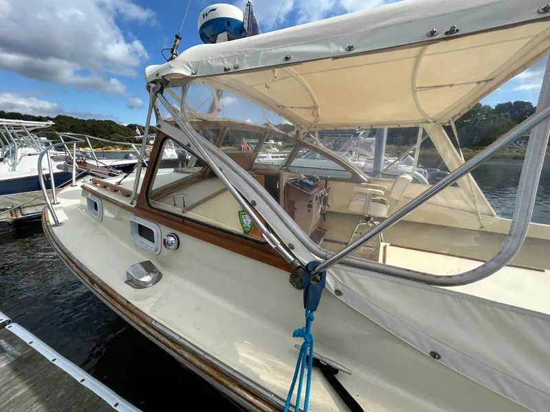 Slide: The Image of 1983 Fortier 26 boat docked, featuring a beige canopy and wooden accents. - 10