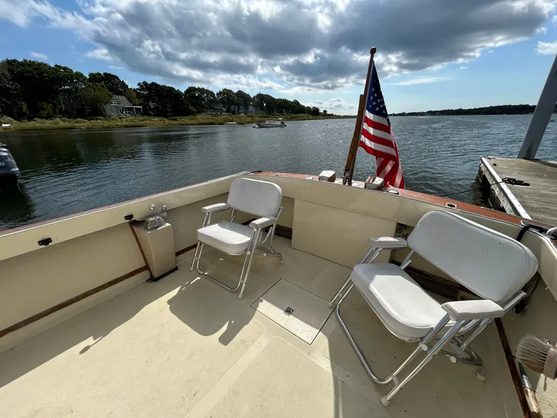 Slide: The Image of 1983 Fortier 26 boat deck with chairs, American flag, and scenic waterfront view. - 12