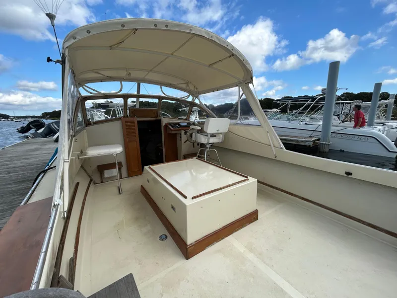 Slide: The Image of 1983 Fortier 26 boat interior with helm, seating, and open deck under blue sky. - 14
