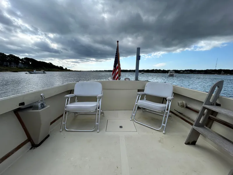 Slide: The Image of 1983 Fortier 26 boat deck with chairs, American flag, and scenic water view. - 15