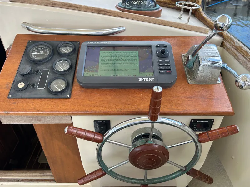 Slide: The Image of 1983 Fortier 26 boat helm with steering wheel, gauges, and navigation system. - 21