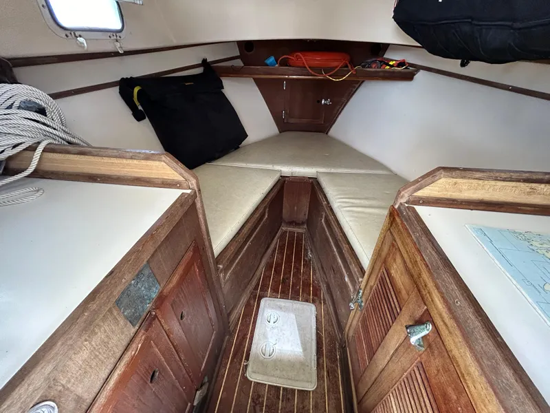 Slide: The Image of 1983 Fortier 26 boat cabin interior with wooden finish and cushioned seating. - 26
