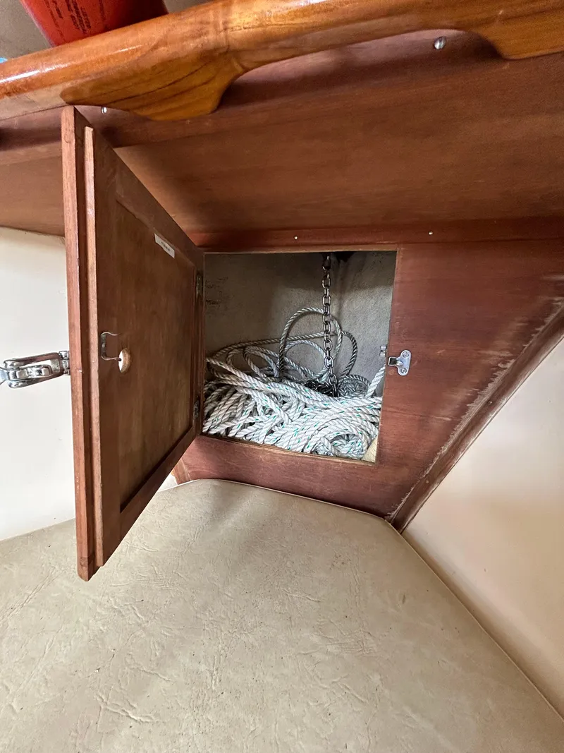 Slide: The Image of Open wooden cabinet on 1983 Fortier 26 boat, revealing coiled ropes inside. - 36