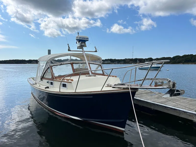 Slide: The Image of 1983 Fortier 26 boat docked on calm water under a partly cloudy sky. - 42
