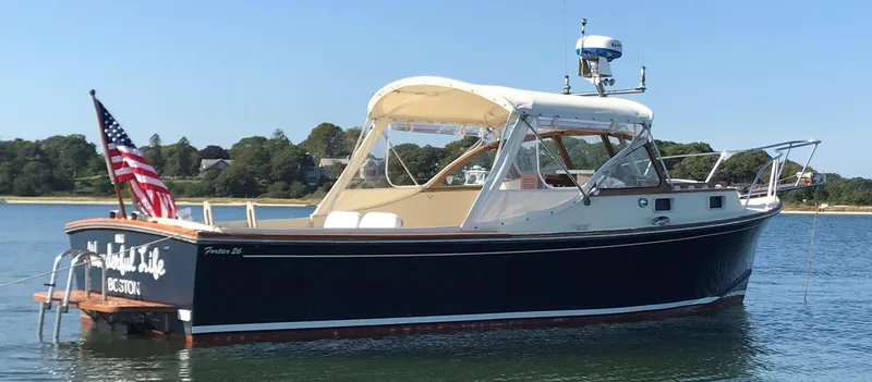 Slide: The Image of 1983 Fortier 26 boat with American flag, anchored in calm waters under clear blue sky. - 48