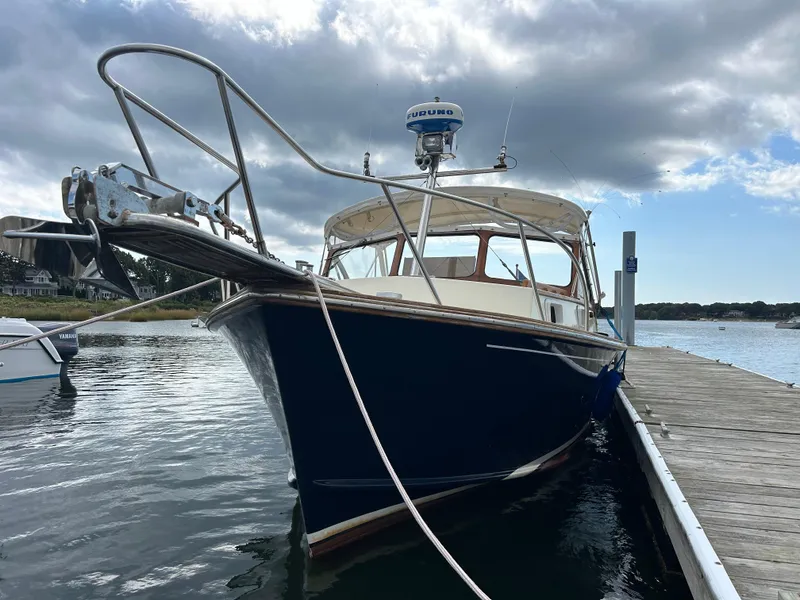 Slide: The Image of 1983 Fortier 26 boat docked on a calm waterway under a cloudy sky. - 6