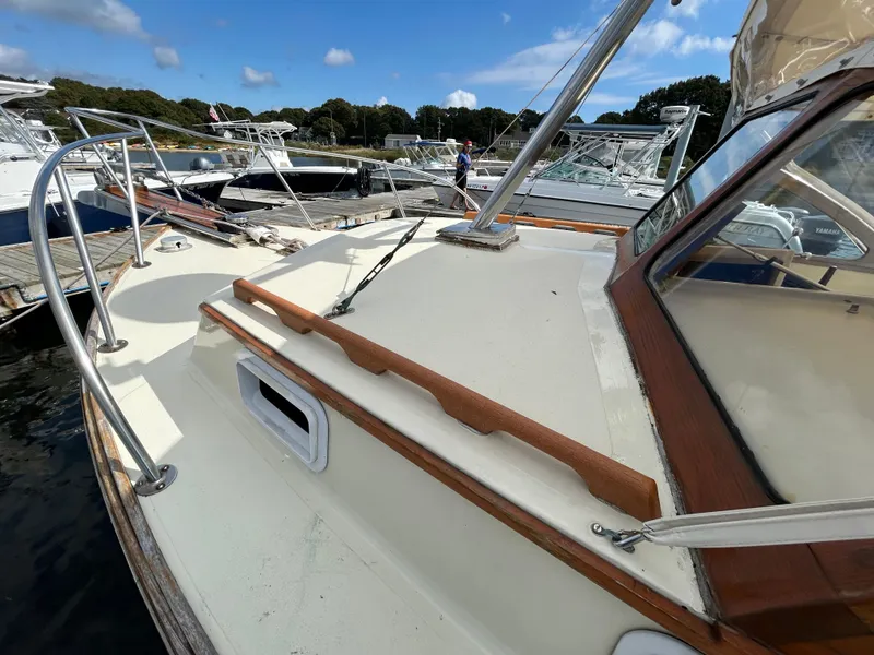 Slide: The Image of 1983 Fortier 26 boat docked, showcasing deck and cabin details under a clear sky. - 8