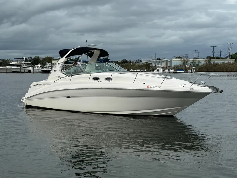 The Image of 2003 Sea Ray 320 Sundancer boat on calm water under cloudy skies. - 0