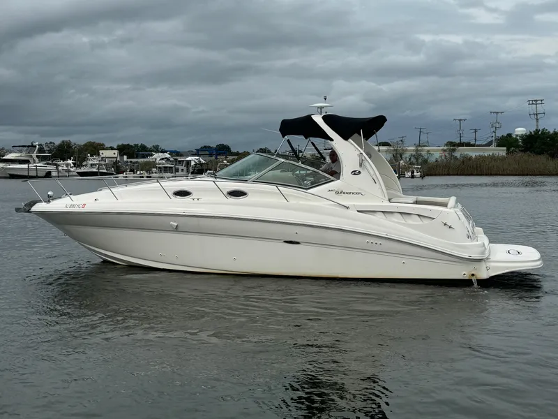 Slide: The Image of 2003 Sea Ray 320 Sundancer boat on calm water under cloudy skies. - 11