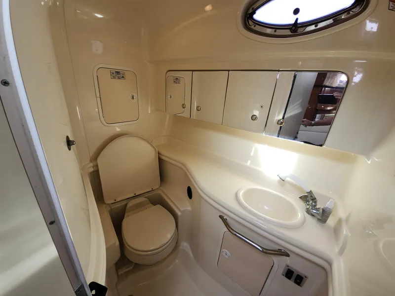 Slide: The Image of 2003 Sea Ray 320 Sundancer bathroom with toilet, sink, and storage cabinets. - 38