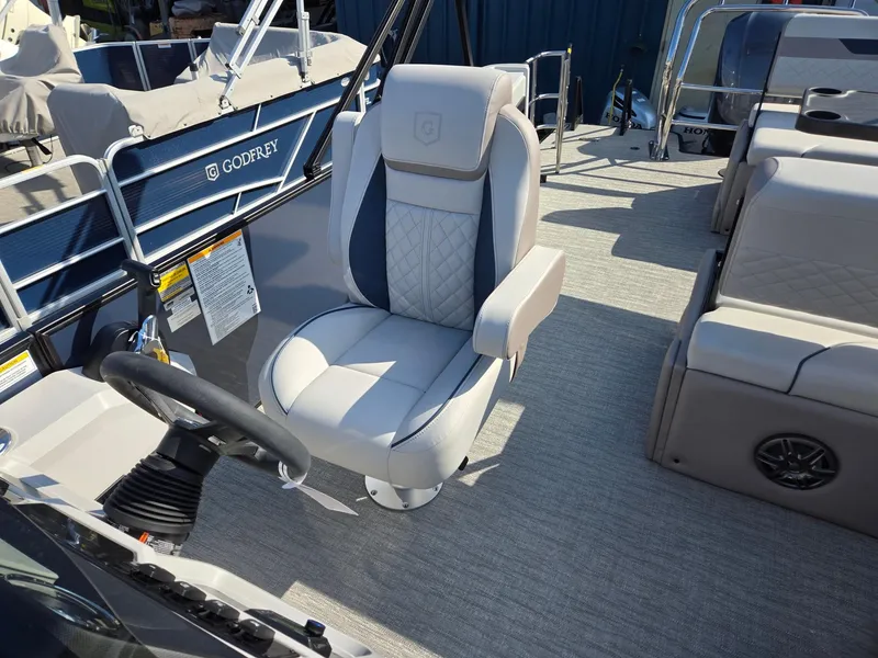 Slide: The Image of 2025 Godfrey SWEETWATER Entertainment 2486 DT boat interior with captain's chair and steering wheel. - 14