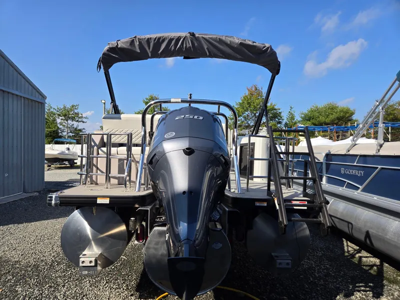 Slide: The Image of 2025 Godfrey SWEETWATER Entertainment 2486 DT pontoon boat with outboard motor, docked outdoors. - 4