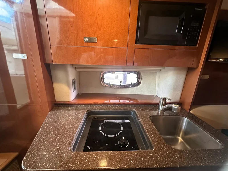 Slide: The Image of 2012 Sea Ray 310 Sundancer kitchen with stove, sink, and microwave. - 6