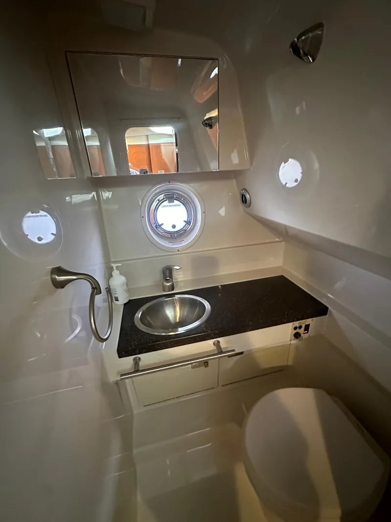 Slide: The Image of 2012 Sea Ray 310 Sundancer bathroom with sink, mirror, and porthole window. - 7