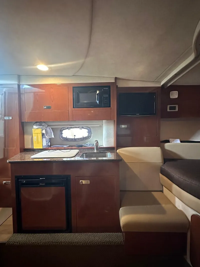 Slide: The Image of Interior of 2012 Sea Ray 310 Sundancer yacht with kitchenette and seating area. - 9