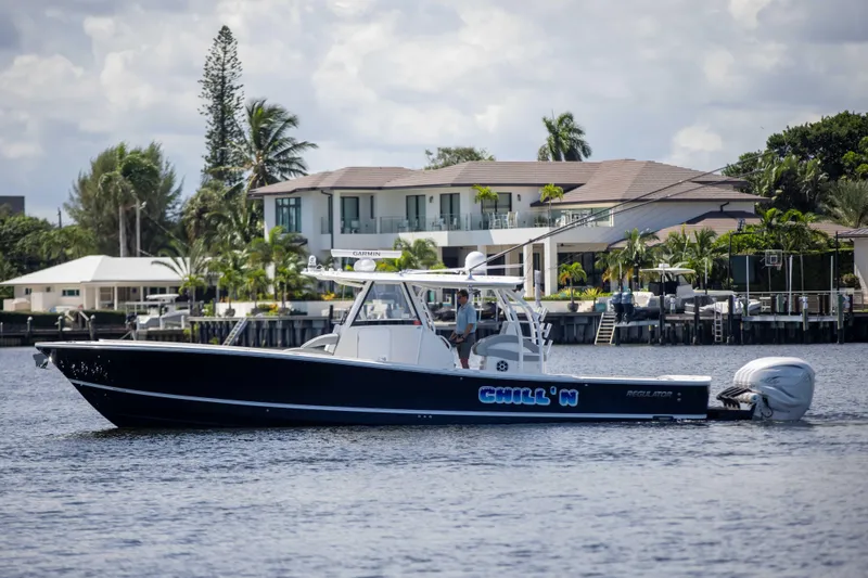 The Image of 2021 Regulator 41 boat cruising on a calm waterfront near luxury homes. - 0