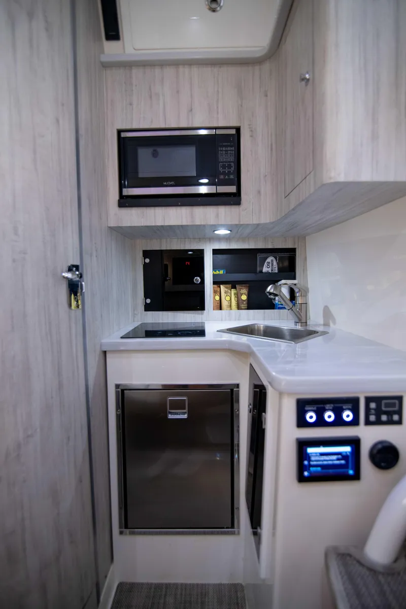 Slide: The Image of 2021 Regulator 41 boat interior kitchen with microwave, sink, and control panel. - 23