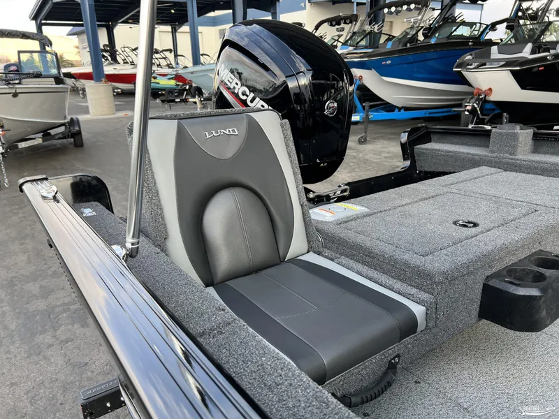 Slide: The Image of 2025 Lund 1675 Adventure Sport boat interior with Mercury engine, featuring gray seating and storage. - 14