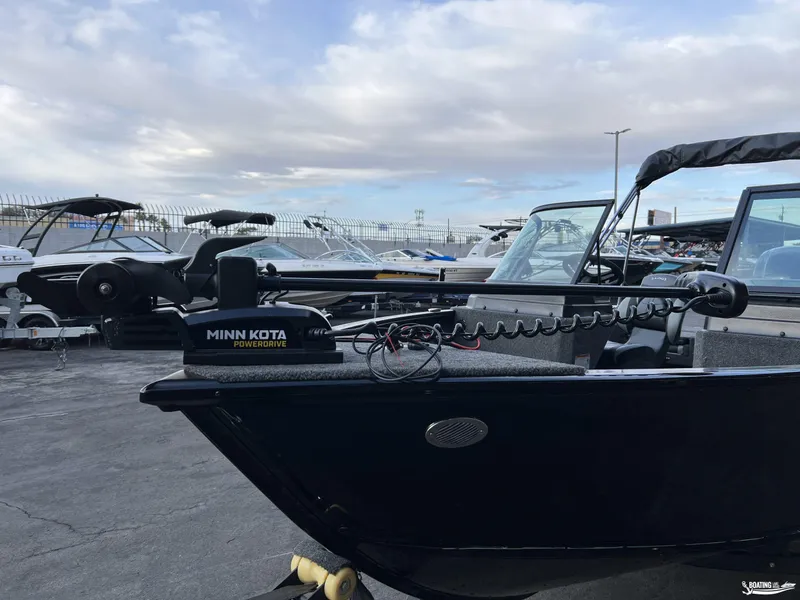 Slide: The Image of 2025 Lund 1675 Adventure Sport boat with Minn Kota PowerDrive motor, docked outdoors. - 5