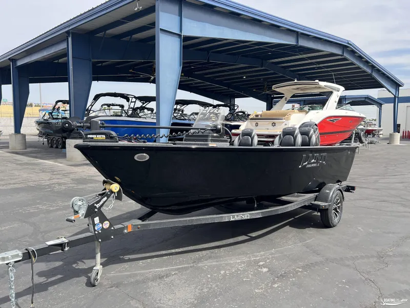 Slide: The Image of 2025 Lund 1650 Rebel XL Blackout Package boat on trailer in marina. - 2