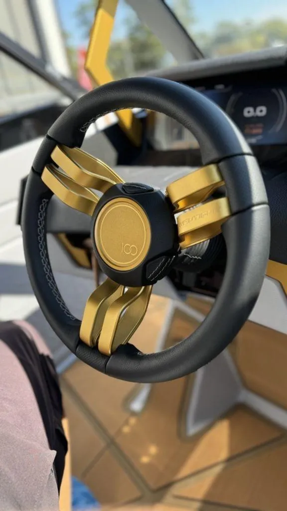 Slide: The Image of Luxury steering wheel of 2025 Nautique Paragon 25 boat, featuring gold accents. - 5