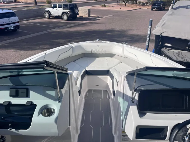 Slide: The Image of 2022 Regal LS2-CM boat interior with white seating and modern dashboard in a parking lot. - 10