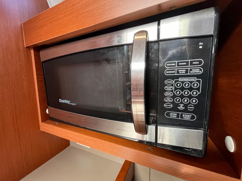 Slide: The Image of Microwave in 2018 Beneteau Oceanis 35.1 yacht kitchen, featuring wood cabinetry. - 37