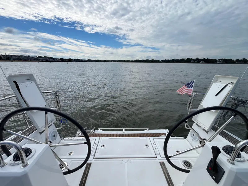 Slide: The Image of Beneteau Oceanis 35.1 sailboat deck view, dual steering wheels, American flag, open water. - 4