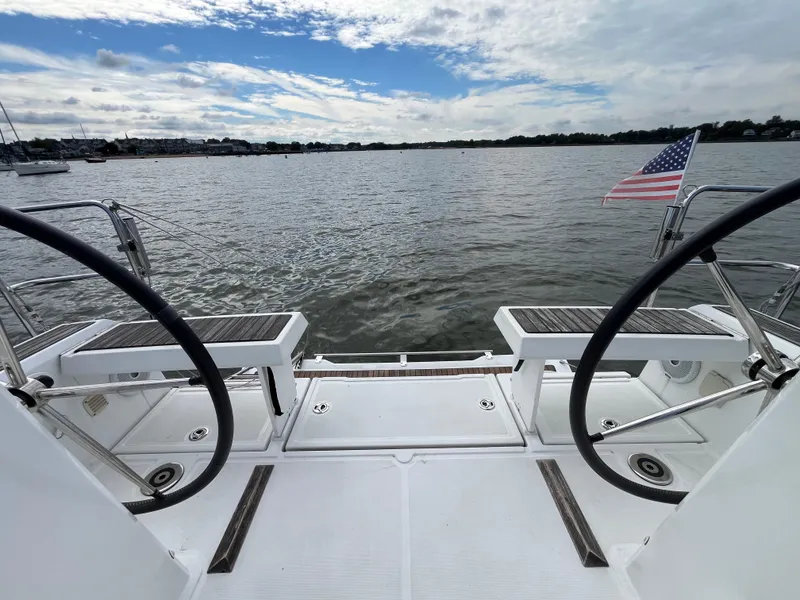 Slide: The Image of 2018 Beneteau Oceanis 35.1 sailboat deck with dual steering wheels, overlooking calm waters. - 5
