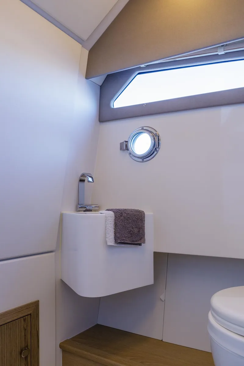 Slide: The Image of 2025 Technohull Alpha 40 yacht bathroom with modern sink and porthole window. - 16