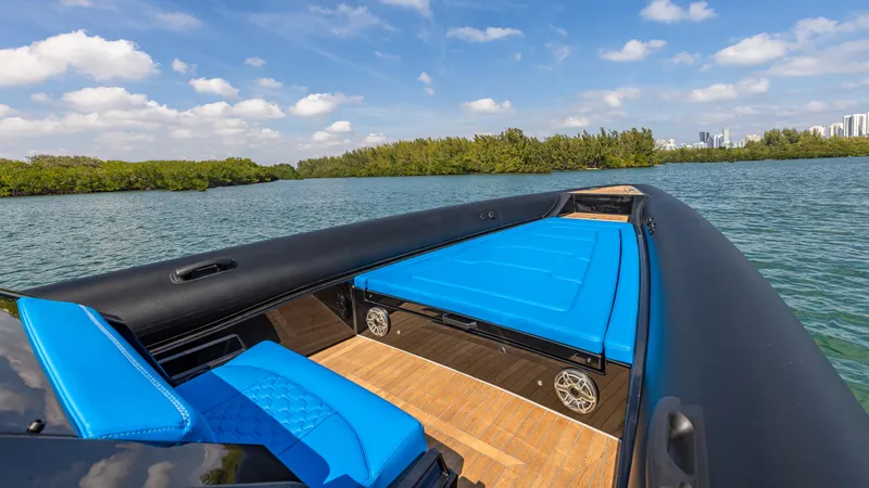 Slide: The Image of 2025 Technohull 38 Grand Sport boat with blue seating, cruising on a scenic lake. - 14