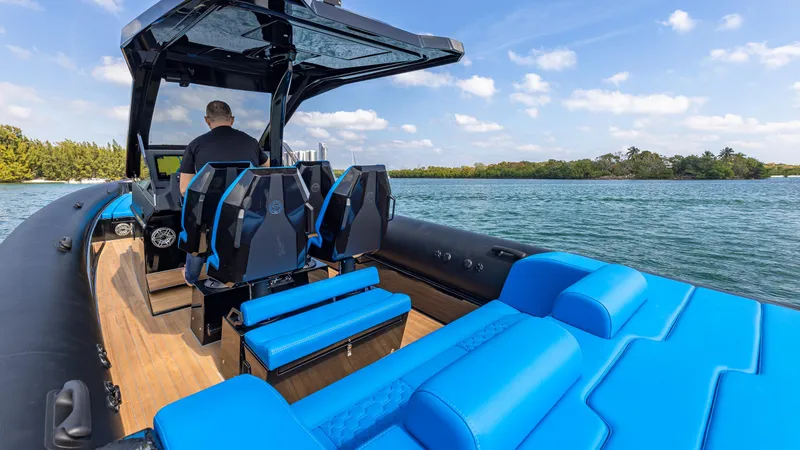 Slide: The Image of 2025 Technohull 38 Grand Sport boat with blue seating on a scenic waterway. - 19