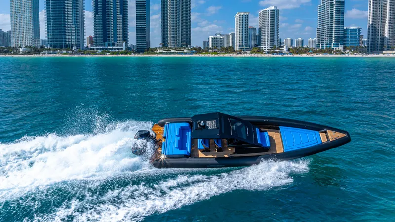 Slide: The Image of 2025 Technohull 38 Grand Sport speeding on blue ocean near city skyline. - 2