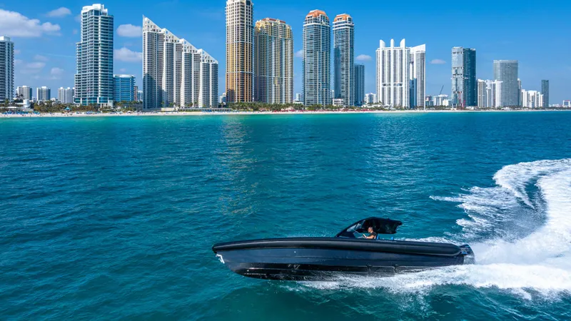 Slide: The Image of 2025 Technohull 38 Grand Sport cruising near city skyline on blue ocean waters. - 2