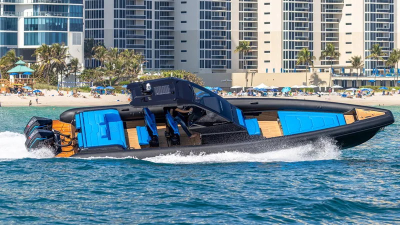 Slide: The Image of 2025 Technohull 38 Grand Sport speedboat cruising near a beach with modern buildings. - 0