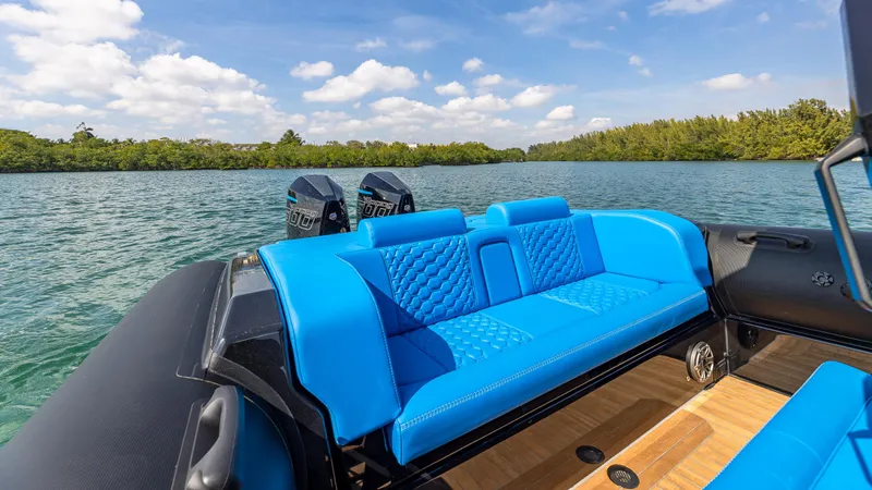 Slide: The Image of 2025 Technohull 38 Grand Sport boat with blue seating on a serene lake. - 2