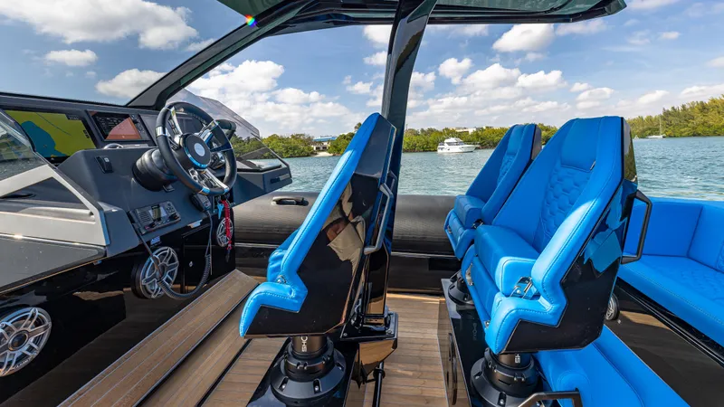 Slide: The Image of 2025 Technohull 38 Grand Sport interior with blue seats and modern dashboard on a sunny day. - 22