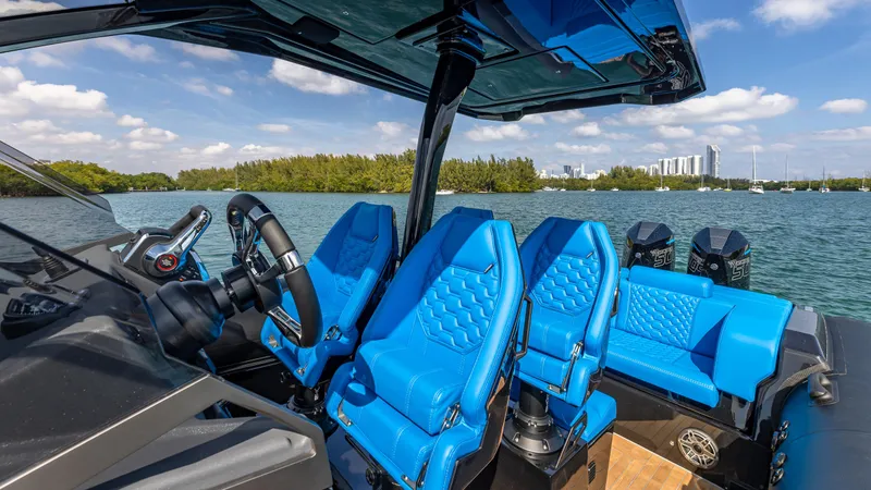 Slide: The Image of 2025 Technohull 38 Grand Sport with blue seats, sleek design, and scenic waterfront view. - 23