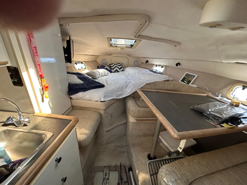 Slide: The Image of Interior of a 1993 Maxum 2700 SCR boat, featuring a cozy cabin with a bed and kitchenette. - 7