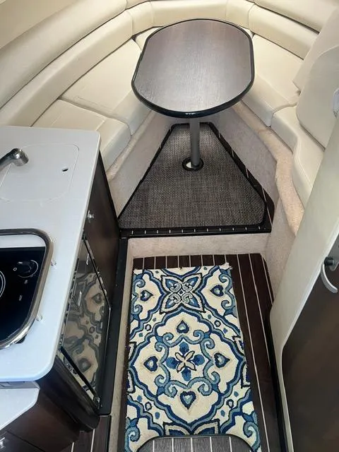 Slide: The Image of Interior of 2017 Monterey 295 Sport Yacht with table, kitchenette, and patterned rug. - 7