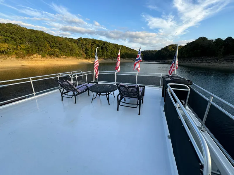 Slide: The Image of Sumerset 20x100 houseboat deck with chairs, flags, and scenic lake view, 2004 model. - 14