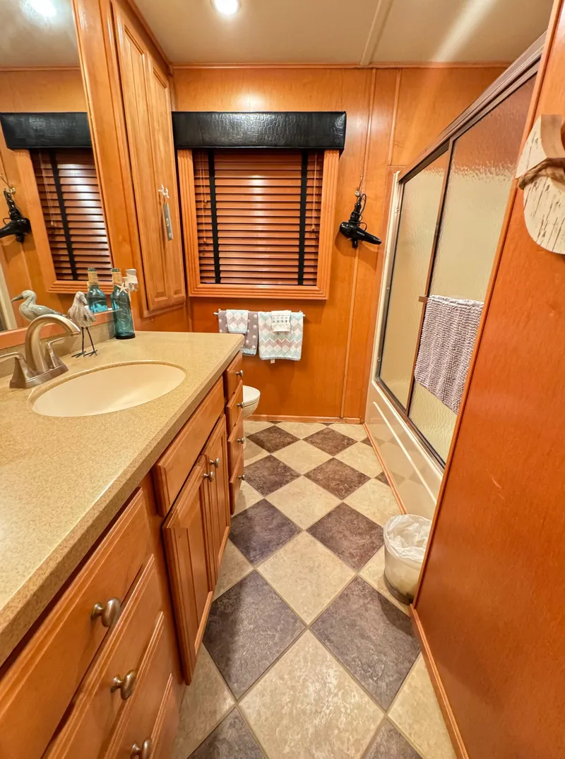 Slide: The Image of 2004 Sumerset 20x100 bathroom with wood cabinets, checkered floor, and shower. - 38