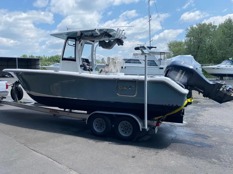 Slide: The Image of 2020 Sea Hunt Gamefish 25 boat on trailer, parked outdoors under a cloudy sky. - 2