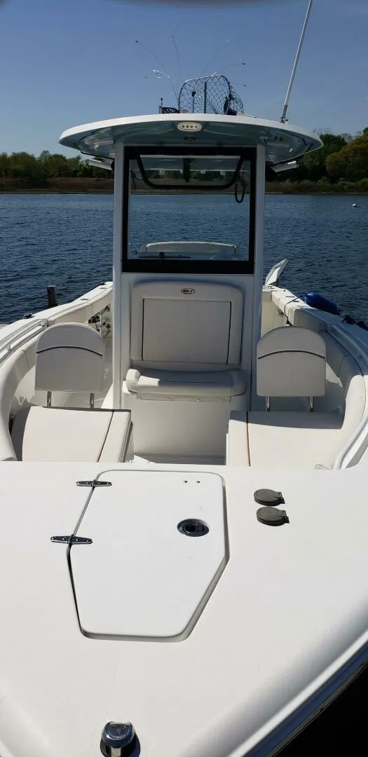 Slide: The Image of 2020 Sea Hunt Gamefish 25 boat on calm water, featuring spacious deck and seating. - 20