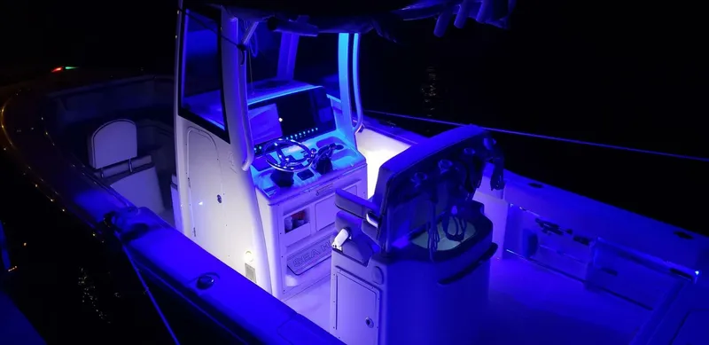 Slide: The Image of 2020 Sea Hunt Gamefish 25 boat interior illuminated with blue LED lights at night. - 23