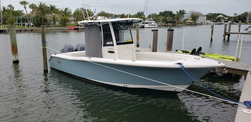 Slide: The Image of 2020 Sea Hunt Gamefish 25 boat docked in a marina, surrounded by calm water. - 5