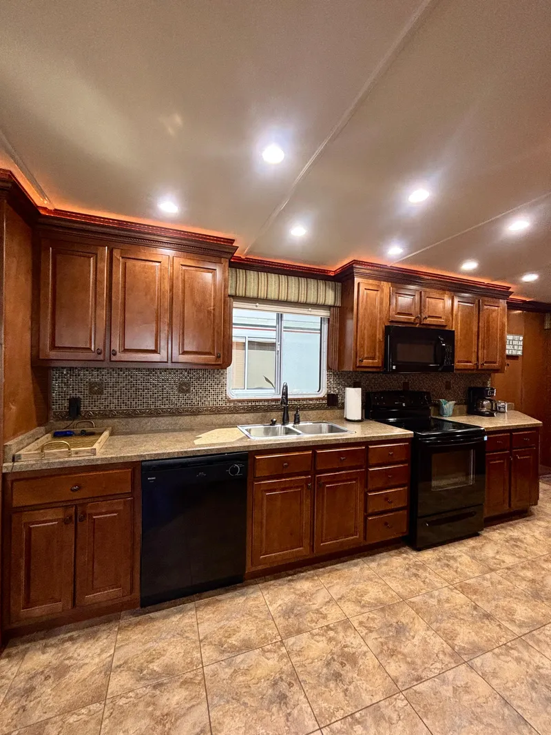 Slide: The Image of Spacious kitchen with wooden cabinets, modern appliances, and tiled flooring in a 2012 Horizon 16x66 model. - 21