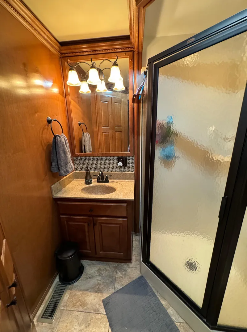 Slide: The Image of Compact bathroom with wooden cabinetry, glass shower, and elegant lighting in a 2012 Horizon 16x66 model. - 36