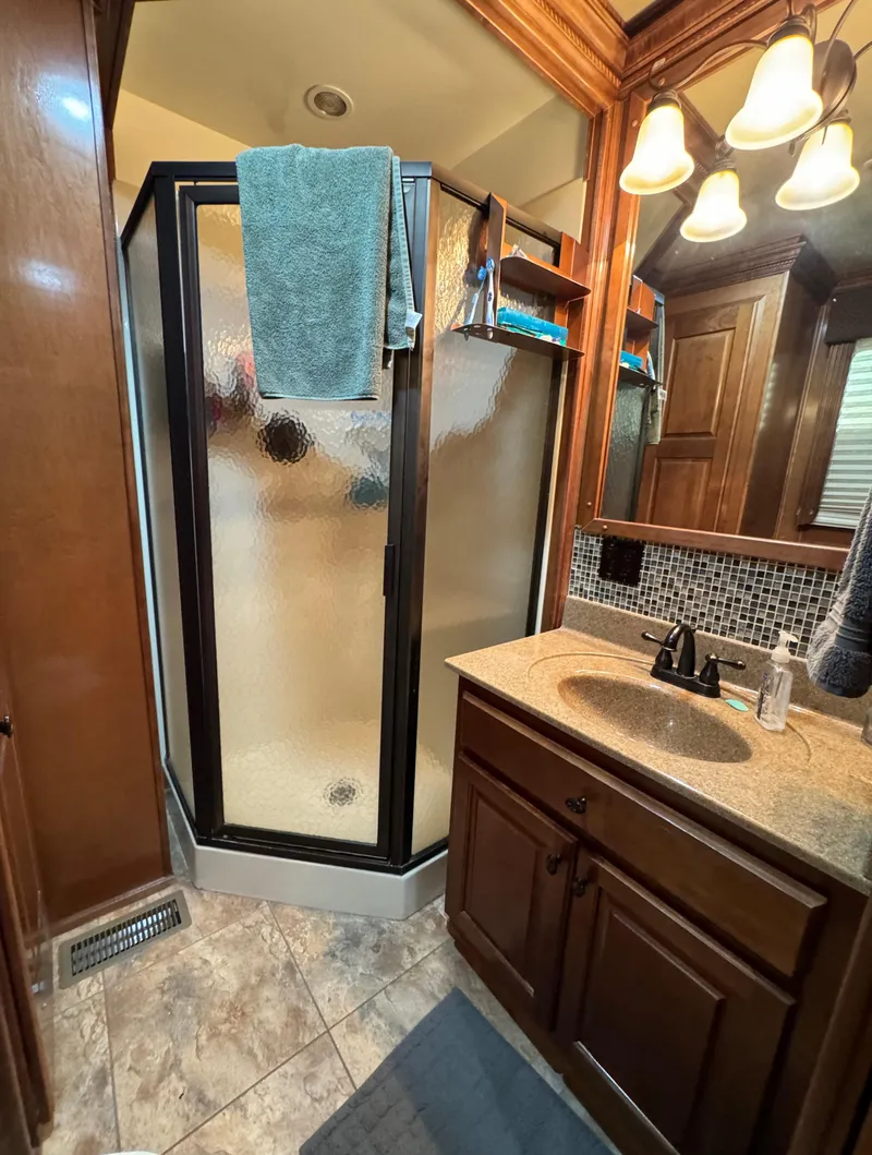Slide: The Image of Modern bathroom with glass shower, wooden cabinets, and elegant lighting in a 2012 Horizon 16x66 model. - 46