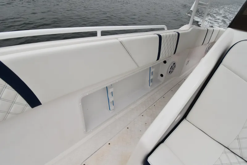 Slide: The Image of 1984 Chris-Craft Scorpion boat interior with white cushioned seating and railing, on water. - 10